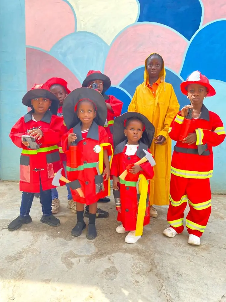 Pupils in red firefighter uniforms holding extinguishers and axes