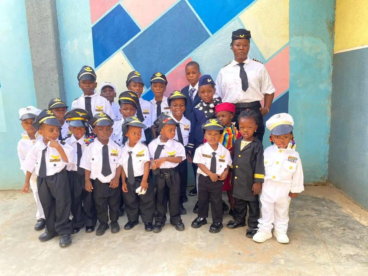 Pupils in pilot uniforms and caps standing with a teacher on Career Day